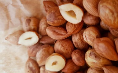 Close-up of a heap peeled hazelnuts, whole and half one, lying on crumpled paper in a bird's eye view