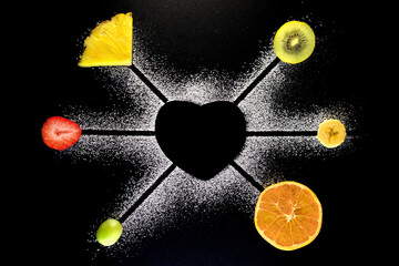 Coraz&oacute;n en silueta de az&uacute;car con frutas frescas y fondo negro