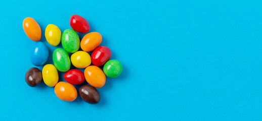 Fototapeta na wymiar Sweet little glazed multi-colored chocolate candies on a blue background