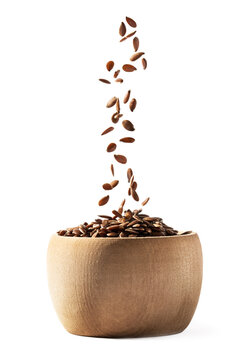 Side View Of Small Wooden Bowl Filling With Linseed Or Flax Seed Falling Down And Isolated On White Background