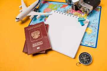 Naklejka na ściany i meble Open notebook with space for text on travel accessories on a yellow background. Planning your summer vacation, travel, and vacation. Russian passports.