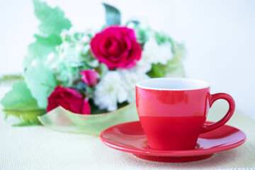 赤いコーヒーカップのコーヒーとバラとスズランの花束（造花）