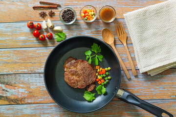 meat with spices in a pan, rosemary, and hot chili peppers on a white wooden table background