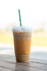 Closeup Plastic glass of iced coffee with milk on blurred background. 