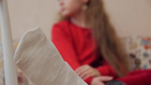 Plaster on leg child girl injured watching TV on the sofa rack focus closeup