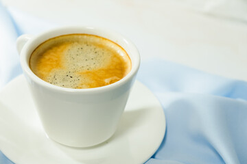 
white cup of coffee on blue cloth