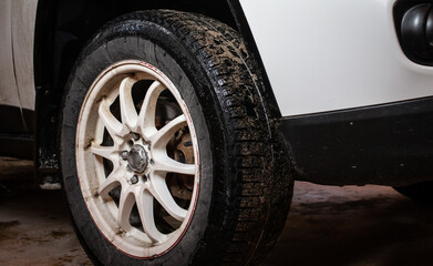 Fototapeta na wymiar February 2021: Muddy snow tires on a white SUV, white rim and slight vignette, Toronto, Ontario, Canada. 