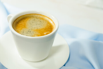 
white cup of coffee on blue cloth