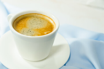 
white cup of coffee on blue cloth
