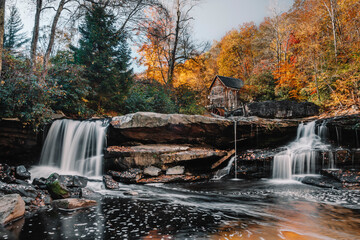 Two waterfalls flow down the rocks of Glade Creek and the gorgeous Glade Creek Grist Mill surrounded by fall foliage in Babcock State Park, Fayette County, West Virginia, USA.