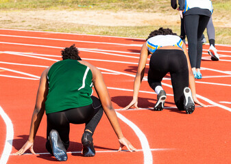 Female sprinters on their mark ready to start their sprint running race outdoors
