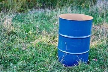 Large bright blue metal open barrel stands on the grass
