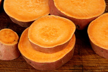 Sliced sweet potato on wooden board background, close up. Raw sweet potatoes or batatas