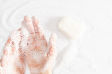 Washing of hands with soap, foam. Cleaning hands. Closeup on woman hands with foam soap bar on white background.