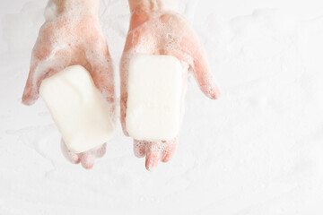 Washing of hands with soap, foam. Cleaning hands. Closeup on woman hands with foam soap bar on white background.