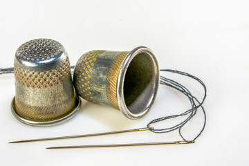 Two thimble and two sewing needles on a white background
