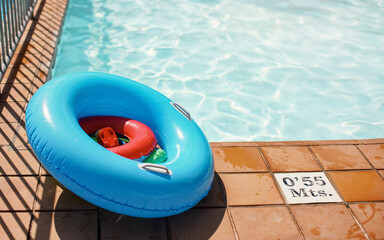 Bright blue inflatable wheel and water toys next to sun lit pool