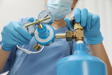 Medical worker checking oxygen tank in hospital room, closeup