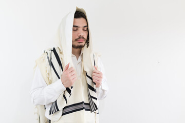 Young Orthodox Jewish man with prayer shawl (tallit) on his head, eyes closed in meditation.