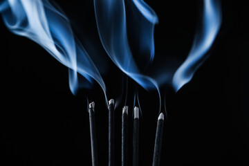 Incense sticks smoldering on black background, closeup