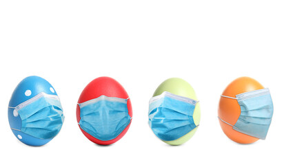 COVID-19 pandemic. Colorful Easter eggs in protective masks on white background