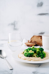 Hummus with broccoli, bread and coffee with water. Breakfast. Middle Eastern dish