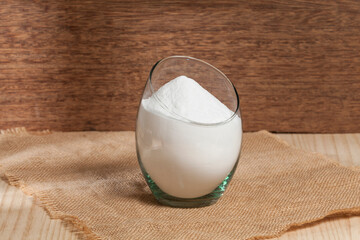 baking soda (sodium bicarbonate) in a glass container; Photo on wooden background.