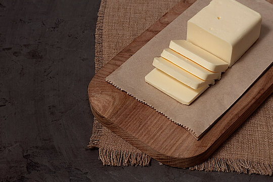 A piece of butter, sliced, on a cutting board, on a black background, no people, horizontal,top view,
