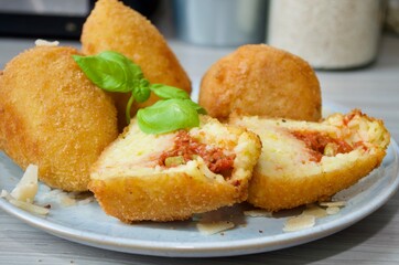 Italienische Reissbällchen gefüllt mit Hackfleischsoße, dekoriert mit Basilikum in Nahaufnahme 
