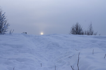 The low sun hangs over a snowy hill. February, 01. 2021.