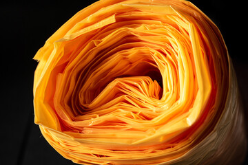 A roll of orange plastic bags as a close-up with many layers.