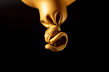 Close-up of a knot of an inflated golden balloon with scenic side light.