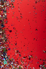 colorful falling confetti on red background.
