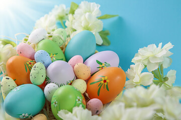 Happy Easter. Colorful Easter eggs and white flower on blue background.