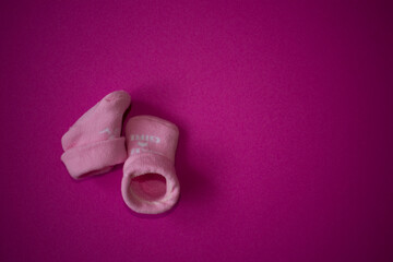 Baby socks on pink background with copy space