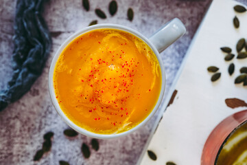 Soupe de courge au curry et baies roses dans un bol sur un fond couleur béton