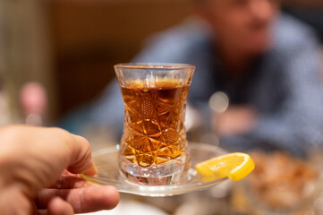 Offering glass of hot black tea to unrecognizable man in cafe
