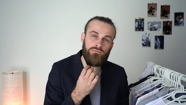 Attractive Young Stylish man in a suit  is looking in a mirror is combing his beard