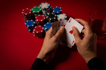 Casino. Poker. Hands of a gambler. Poker player. Game chips and dice lie on the table against a red background. Game chips for betting in gambling. Dice. Poker chips. 