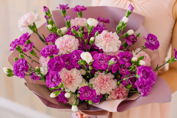 Beautiful spring bouquet of purple carnations in the hands of a young woman for a gift