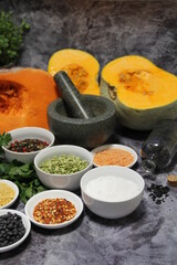 colorful spices and legumes, fresh parsley and stone mortar, pepper, hot pepper, coarse rock salt, black beans and yellow lentils and colored pepper, orange pumpkin sliced