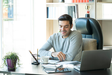 Young businessman using laptop computer notebook for work. Relaxed young man drinking coffee.