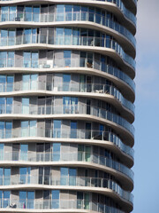 close-up of a modern block of flats showing wavy glass balconies and patterns of windows