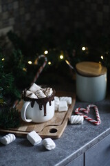 a cup with Christmas cocoa and marshmallows on a caramel background and a Christmas tree garland