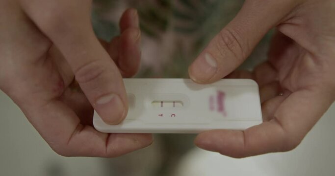 close-up of a positive pregnancy test in fragile female hands