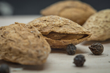 Unpeeled almonds next to peas of pepper .