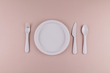 a set of plastic dishes spoon fork knife gray plate on the table