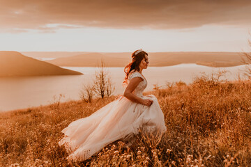 bride in white dress and suit are walking on tall grass in field in summer