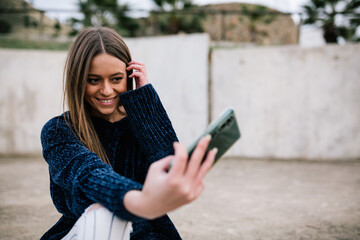 young woman with blond hair taking a selfie on the street. Woman taking a selfie.