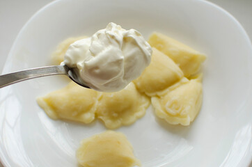 Put sour cream in stuffed dumplings. Traditional Russian home cooking.